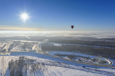 Hot air balloon flying across snow covered landscape