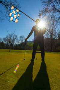 Shadow of man playing with ball on grass