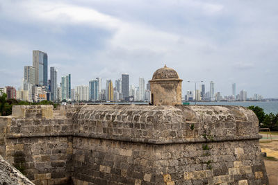 Contrast of ancient structure and modern buildings against sky in city