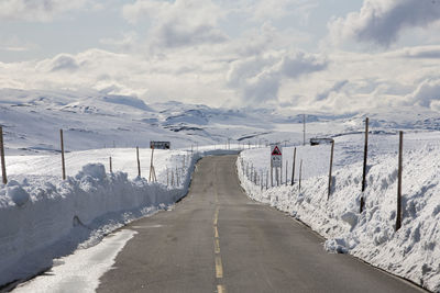 Road amidst snow covered mountains against sky