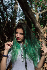 Portrait of beautiful young woman against trees