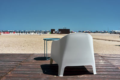 Chairs on beach against clear sky on sunny day