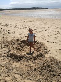 Full length of girl standing on beach against sky