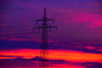 Low angle view of electricity pylon against dramatic sky