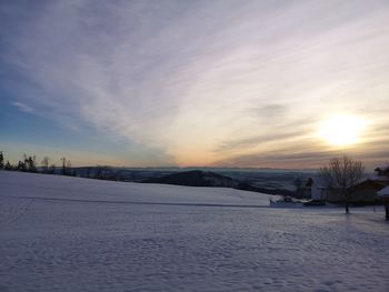 Scenic view of snow covered field against sky at sunset
