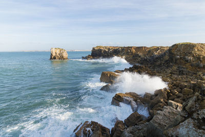 Scenic view of rock formations by sea against sky