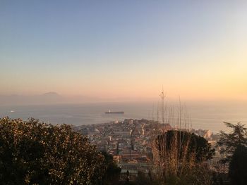 High angle view of townscape by sea against sky during sunset