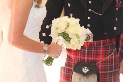 Midsection of bride and bridegroom with flower bouquet