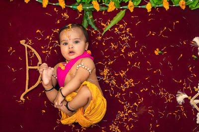 Cute indian boy dresses as lord rama with bow and flowers from top angle