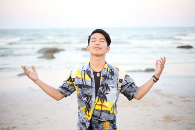 Mid adult man standing at beach against sky