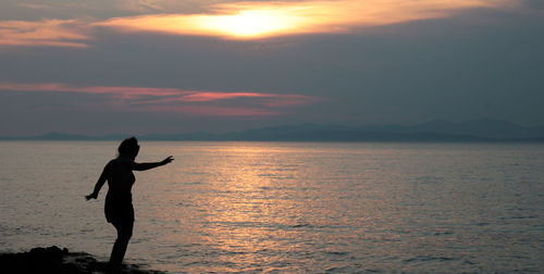 Silhouette man standing on beach against sky during sunset