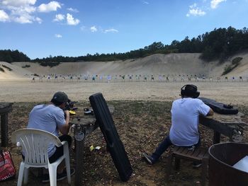 Rear view of fiends practicing with rifle at shooting range