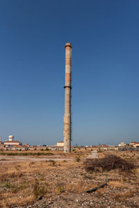 View of old tower on field against clear blue sky