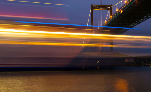 Light trails on bridge against sky at night