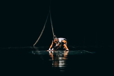 Man jumping in water against black background