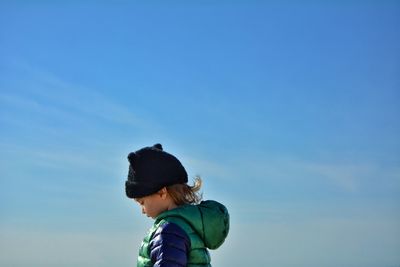 Boy looking away against blue sky