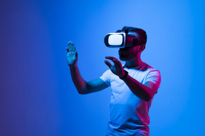 Side view of young man photographing against blue background