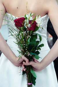 Midsection of bride holding rose bouquet