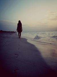 Rear view of woman on beach during sunset