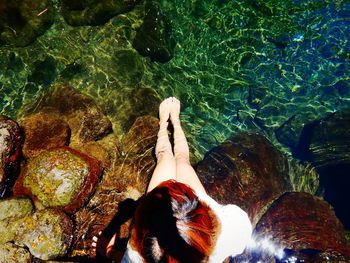 Low section of woman by rock in water