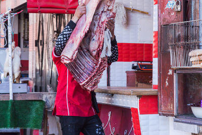 Butcher holding meat while standing at market stall