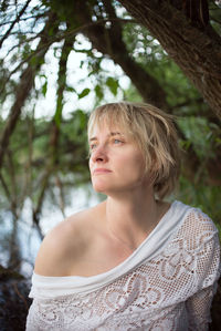 Thoughtful beautiful woman looking away in forest