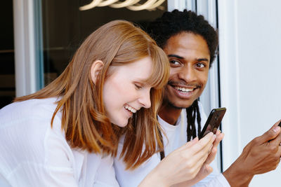 Portrait of smiling young woman holding smart phone