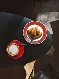 High angle view of cappuccino and croissant on table