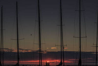 Silhouette masts against sky during sunset