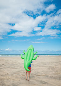 Rear view of boy walking on beach against sky