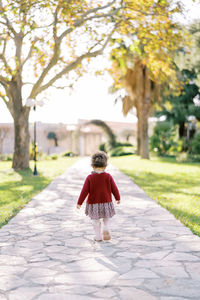 Rear view of girl walking on footpath in park