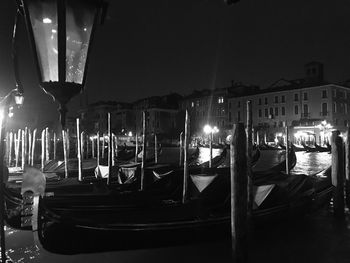 Boats moored in canal against sky at night