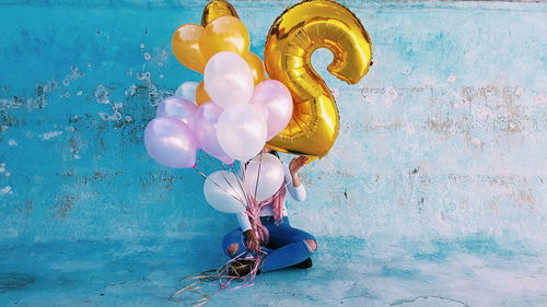 Multi colored balloons hanging against wall