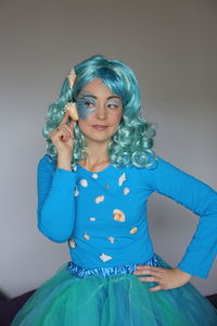 Young woman wearing hat standing against blue background