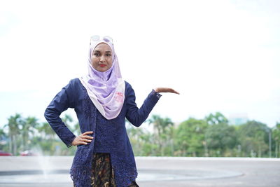 Portrait of young woman standing against the sky