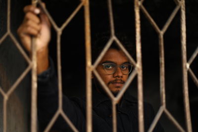 Portrait of man seen through chainlink fence