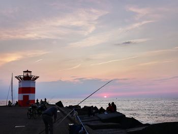 People on beach against sky during sunset
