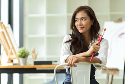 Portrait of young woman sitting on wall