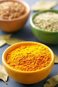 High angle close-up of curry powder with cumin and oregano in bowls on table