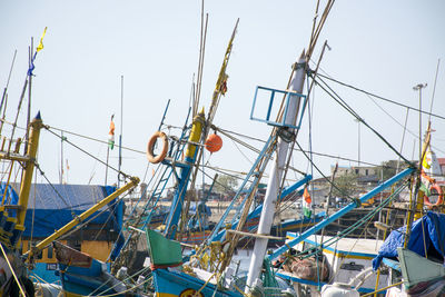 Fishing boats moored at harbor against clear sky