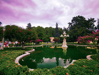 Scenic view of lake in park against cloudy sky