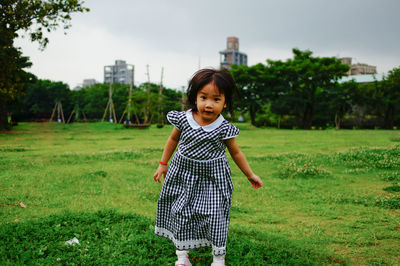 Portrait of girl standing on grassy field