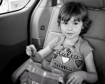 Portrait of girl holding bucket toy in car