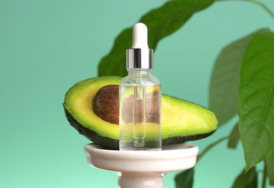 Avocado oil. cosmetic pipette with drops of oil. transparent bottle. half of avocado. close up. 