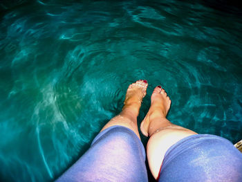 Low section of woman relaxing in swimming pool