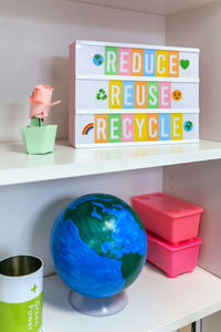 Lightbox with text reduce, reuse, recycle and earth globe on shelf in classroom