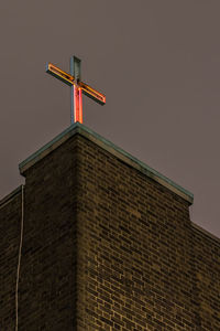 Low angle view of cross on building against clear sky