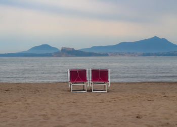 Empty chair on beach against sky