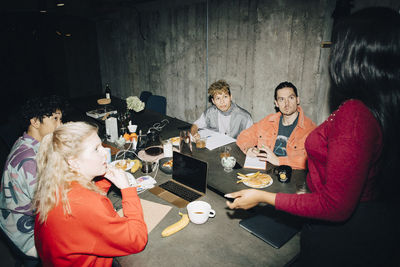 Side view of entrepreneur gesturing while talking to coworkers at table in creative office