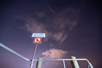 Low angle view of road sign against sky at night in geneva